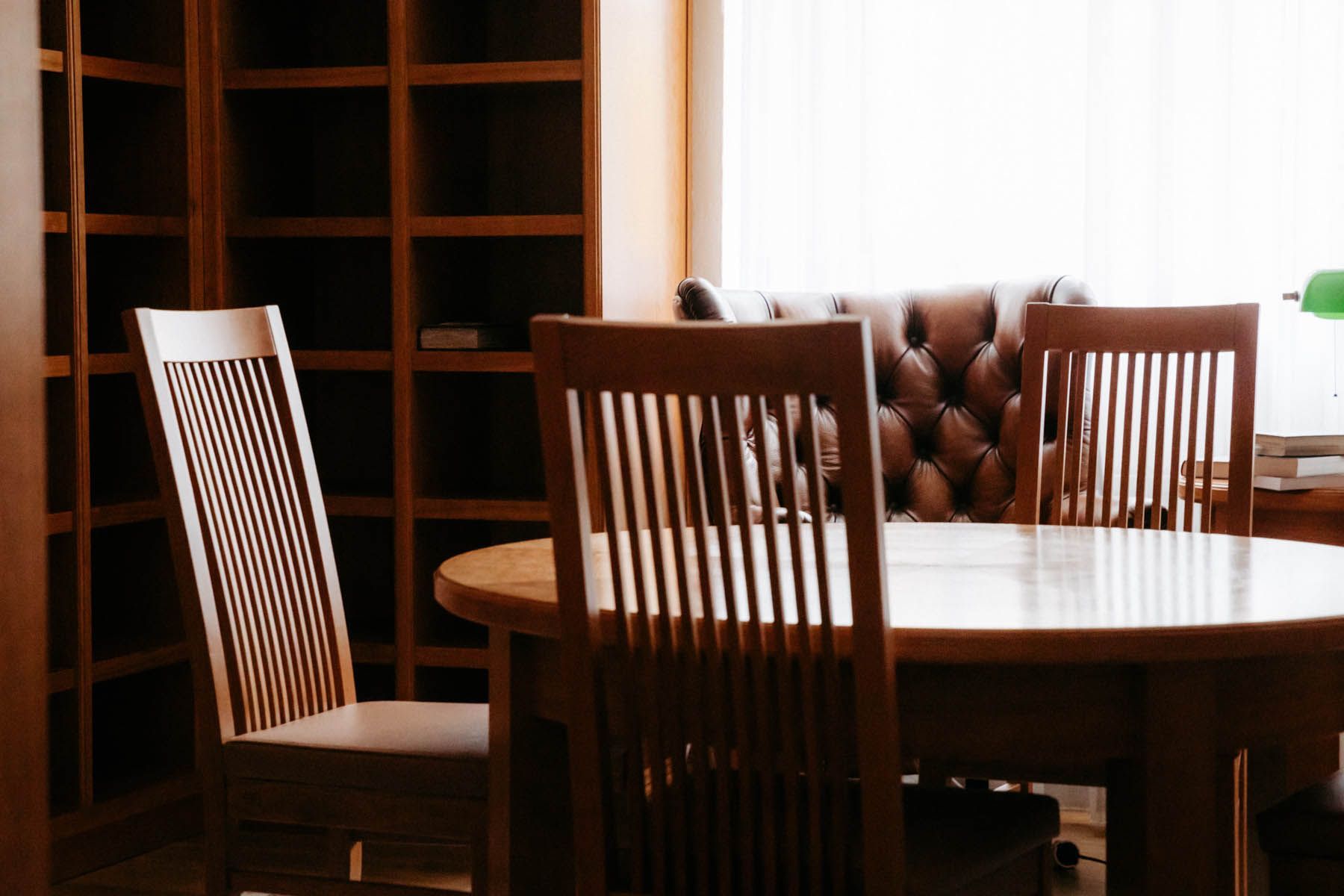 Holztisch und Stühle in einem Raum mit gepolstertem Ledersofa und Bücherregal.