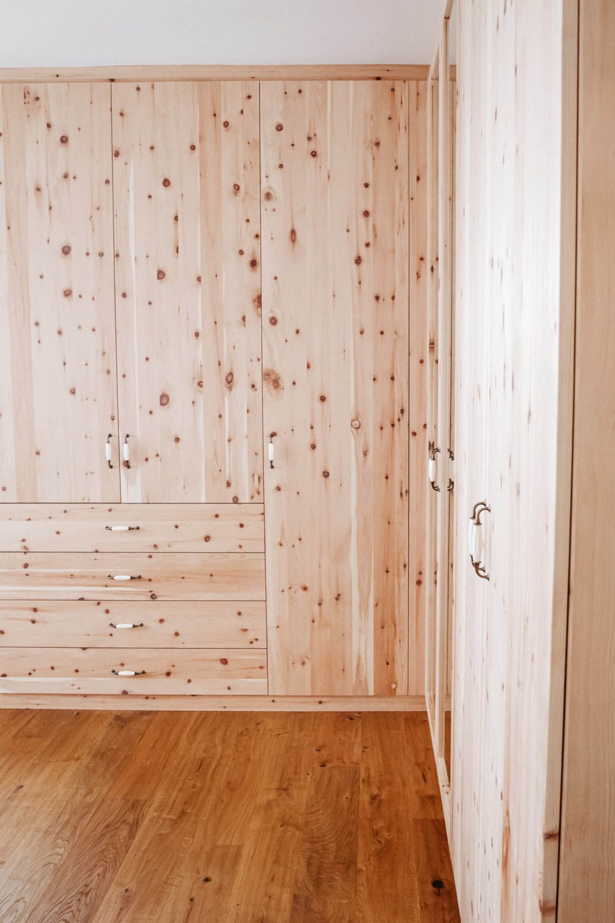 Heller Holzschrank mit Schubladen und Türen, auf einem Holzboden.