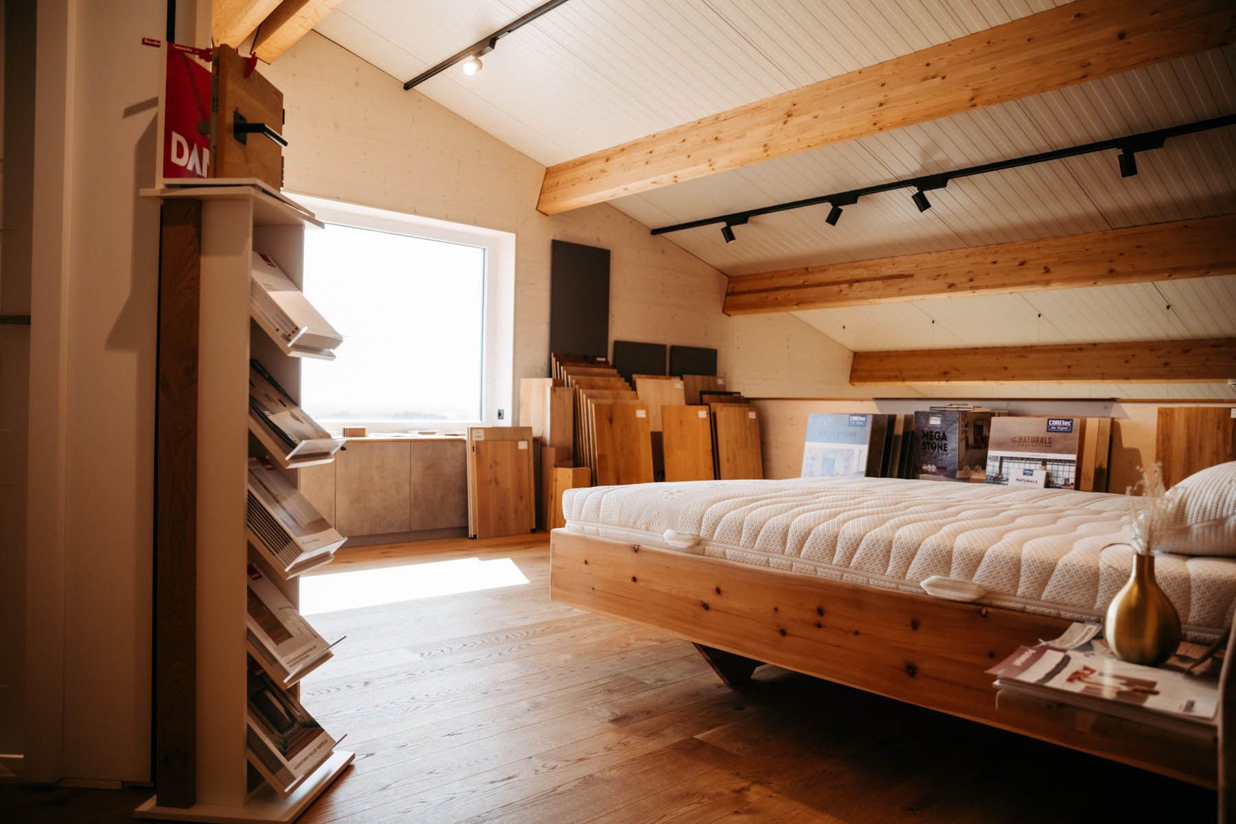 Schlafzimmer-Ausstellungsraum mit Holzbett, Mustern und Fenster.