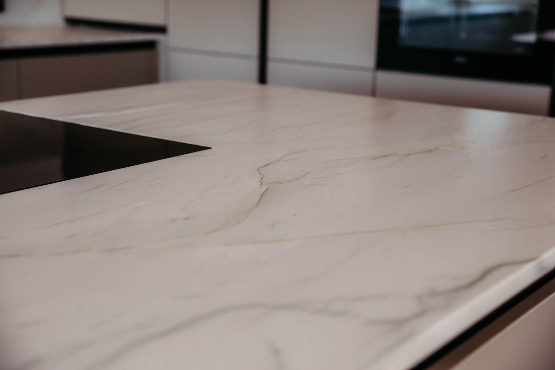 Nahaufnahme einer hellen Marmorarbeitsplatte mit Maserung, Teil eines modernen Küchendesigns.