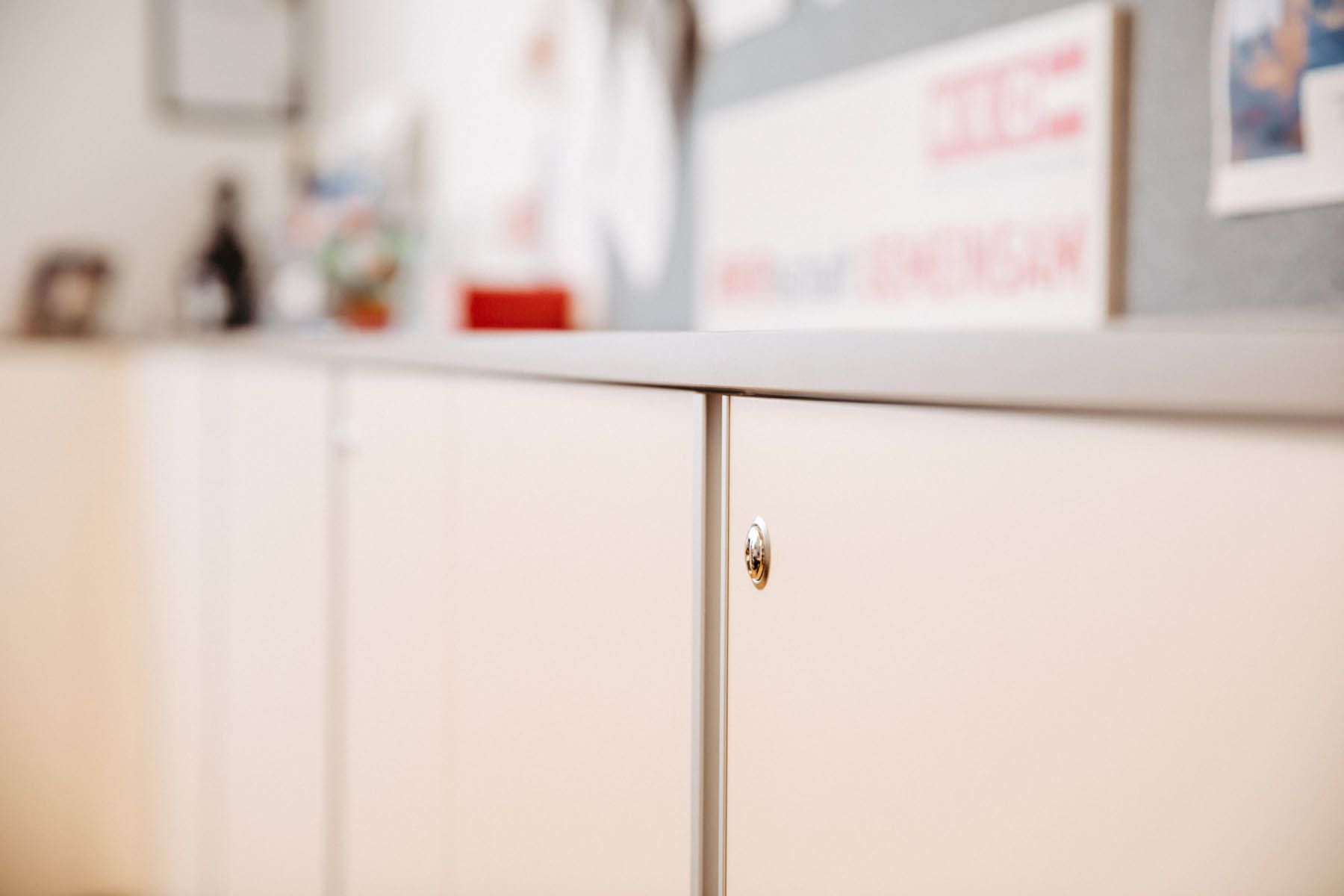 Cremefarbene Schranktüren mit silbernem Griff in einer Büroumgebung.