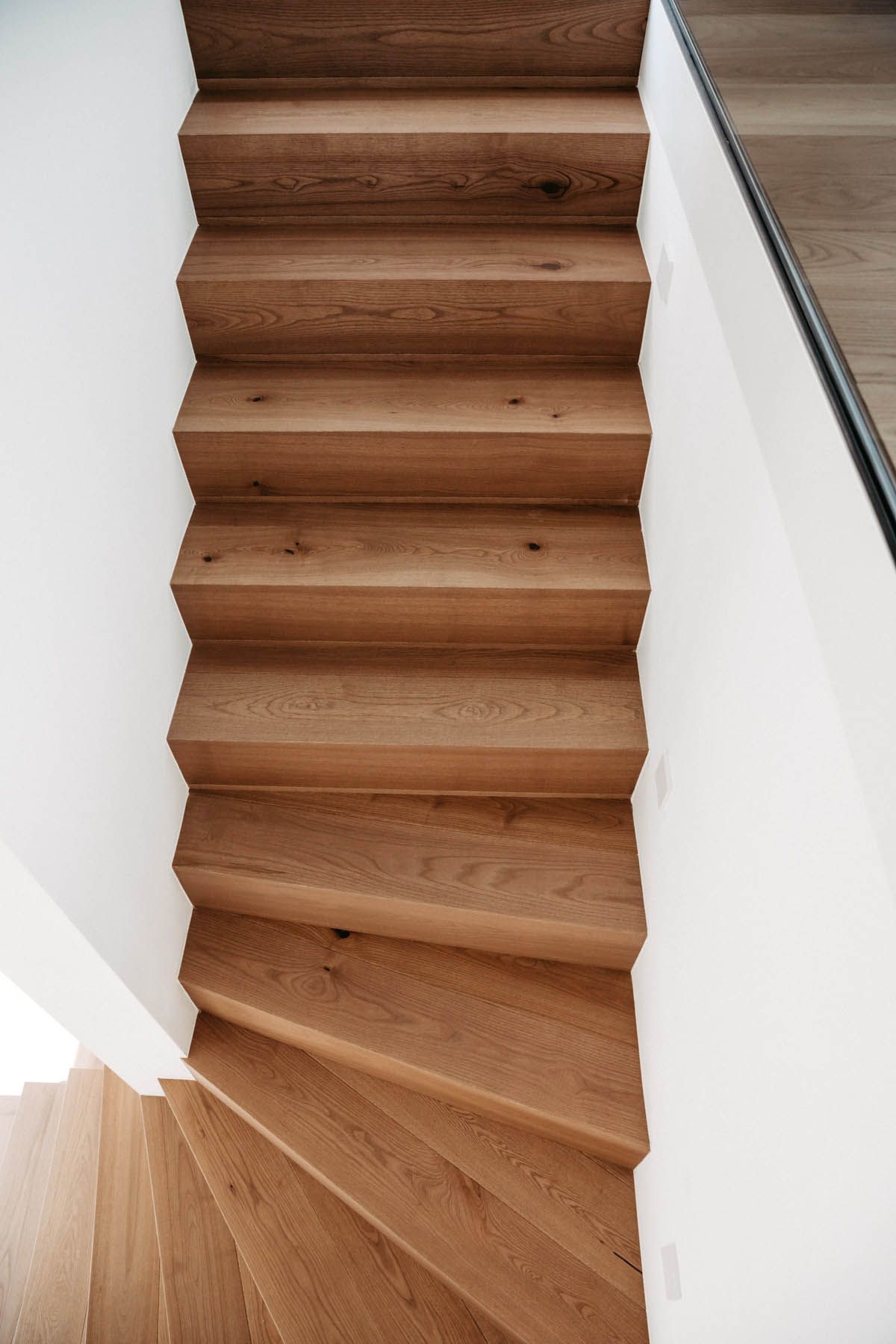 Holztreppe mit Stufen, weiße Wände.