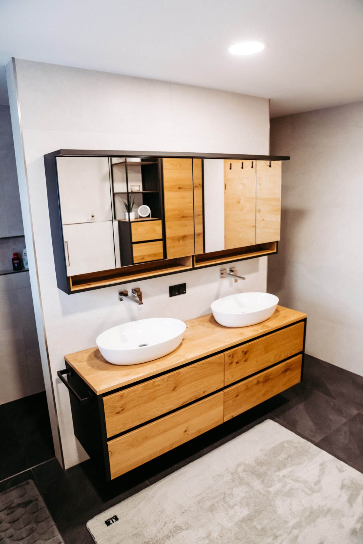 Modernes Badezimmer mit einem Holzwaschtisch, zwei Waschbecken und einem großen Spiegelschrank.