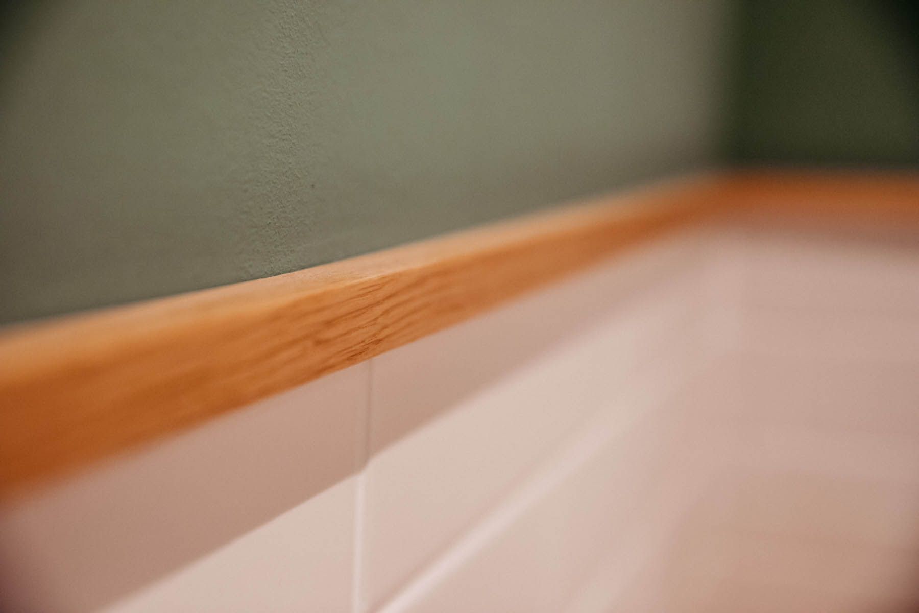 Holzverkleidung auf weißer Verkleidung vor einer grünen Wand.