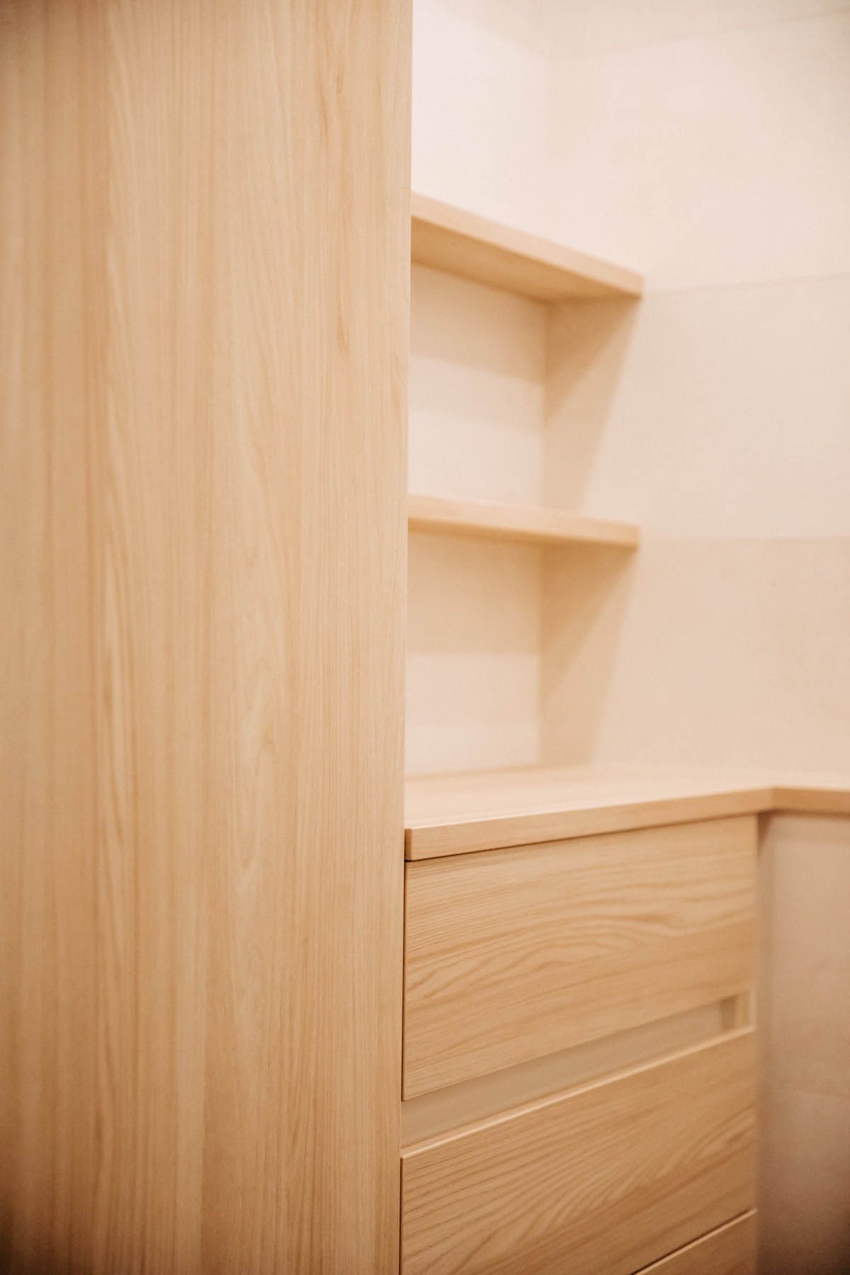 Einbauschrank aus Holz mit Schubladen und Regalen in einem hellen Raum.