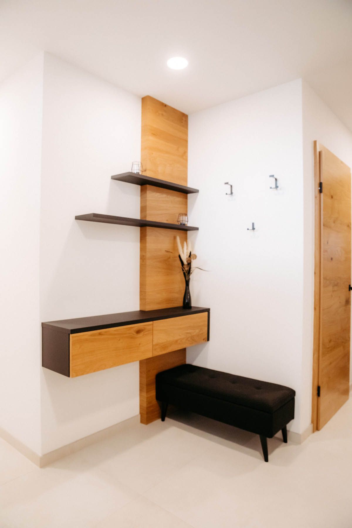 Flur mit Holzregalen, Schrank, Bank und einer Tür. Weiße Wände und Holzakzente.