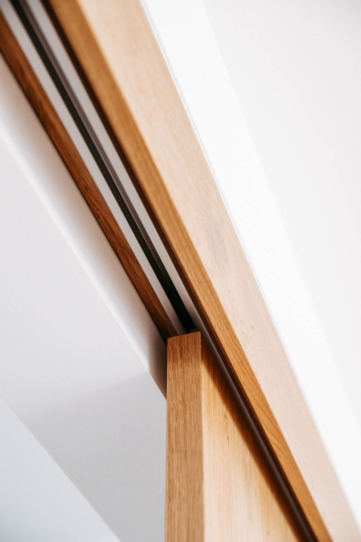 Hölzerne Schiebetürschiene vor einer weißen Decke.