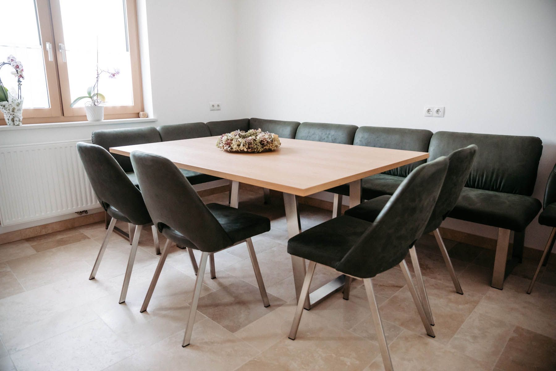 Ein quadratischer Esstisch aus Holz mit dunkel gepolsterten Stühlen und einer eingebauten Eckbank in einem Raum.