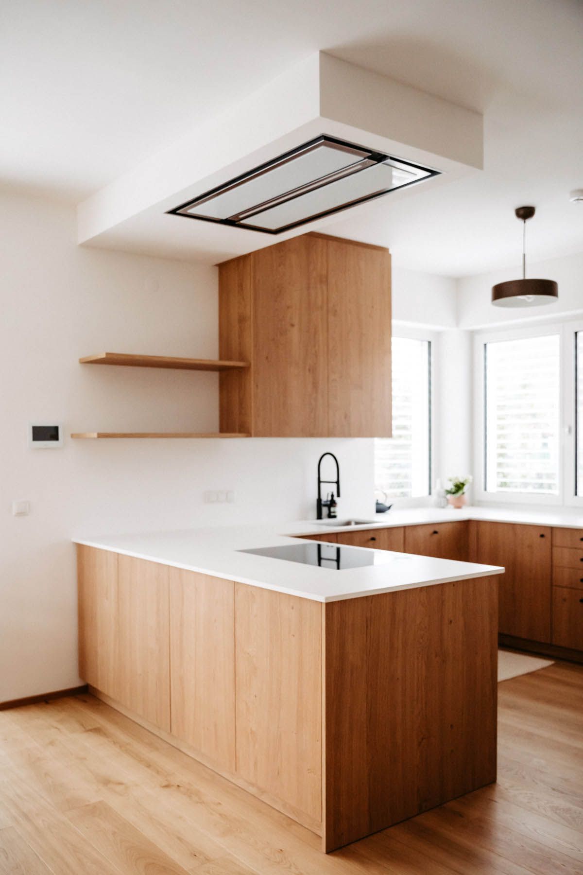 Moderne Küche mit Holzschränken, weißen Arbeitsplatten und einer Kochinsel.