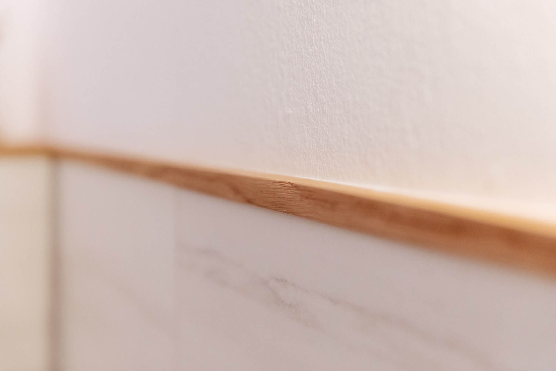 Eine Nahaufnahme einer weißen Wand mit einer dünnen Holzverkleidung.