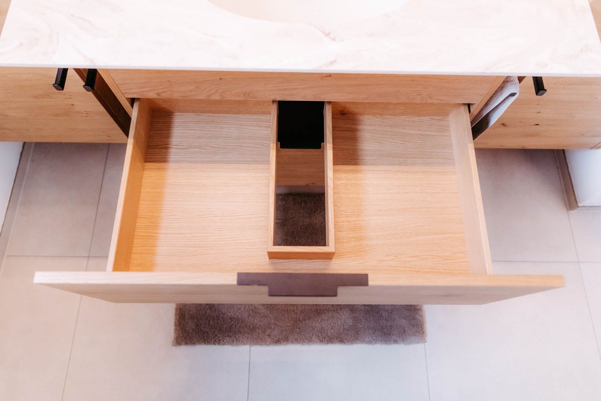 Offene Badezimmerschublade aus Holz mit einem kleinen Organizer.