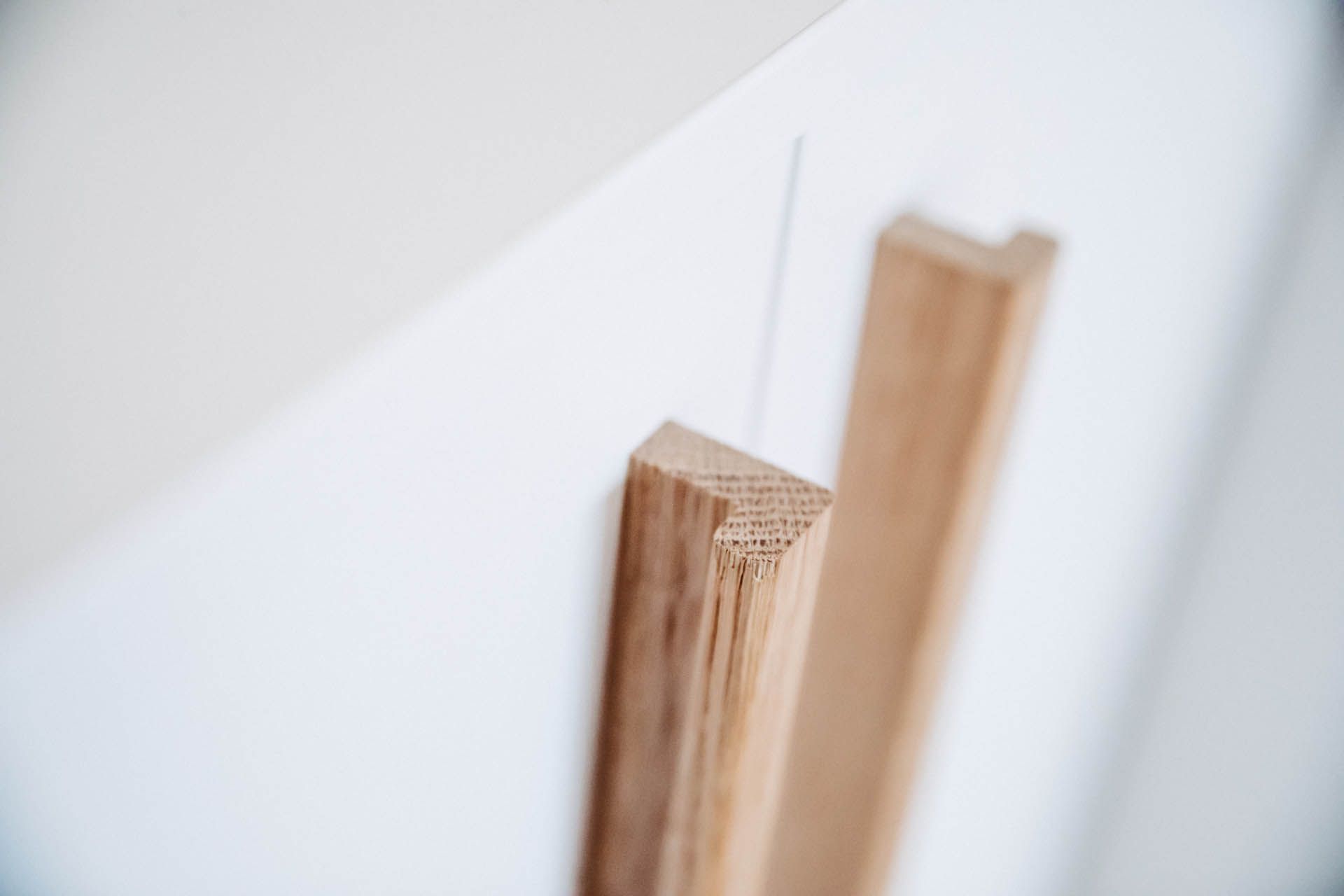 Hölzerne Türgriffe an einem weißen Schrank. Nahaufnahme.