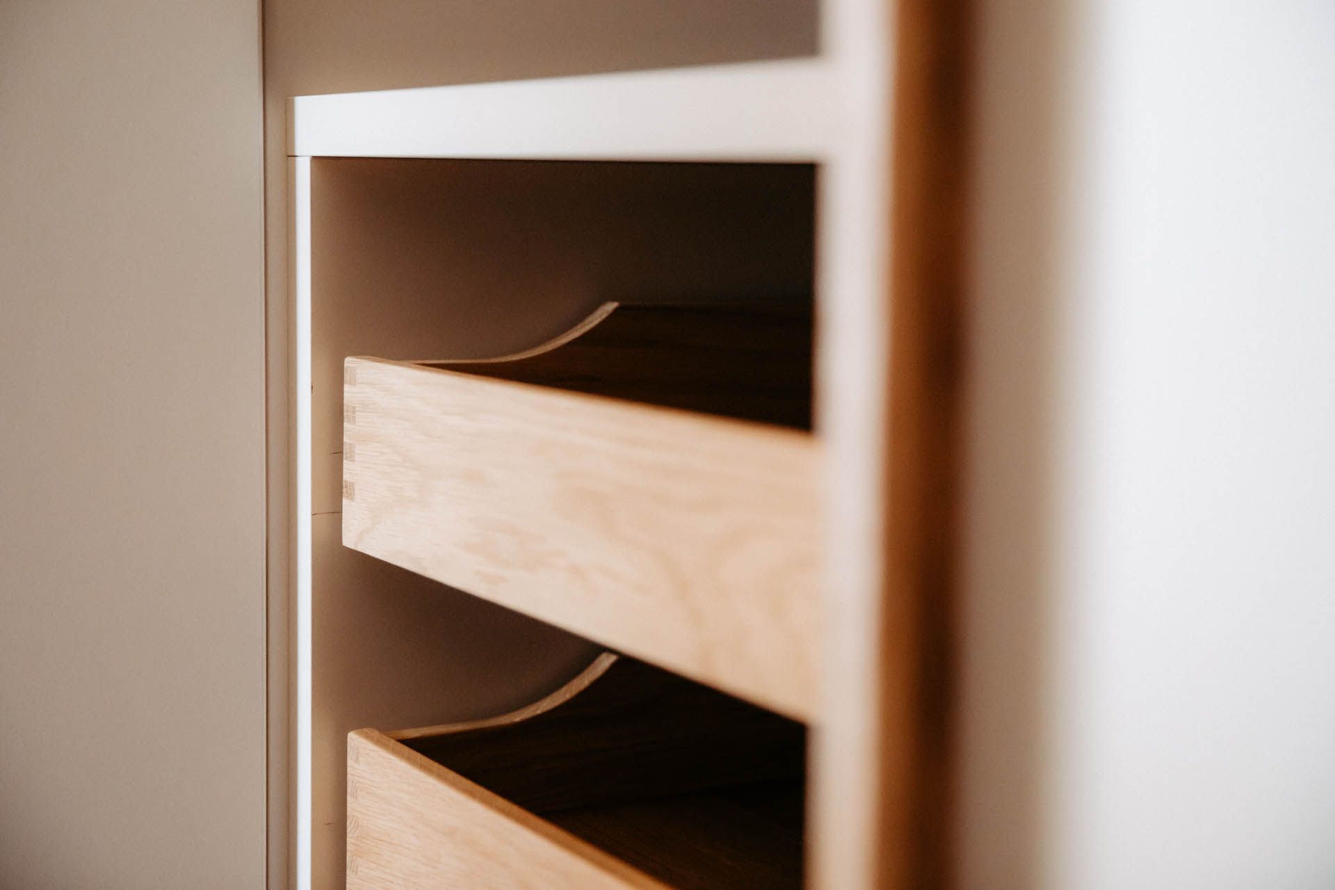 Holzschubladen in einem Einbauschrank mit natürlicher Holzmaserung und geschwungenen Schubladenfronten.