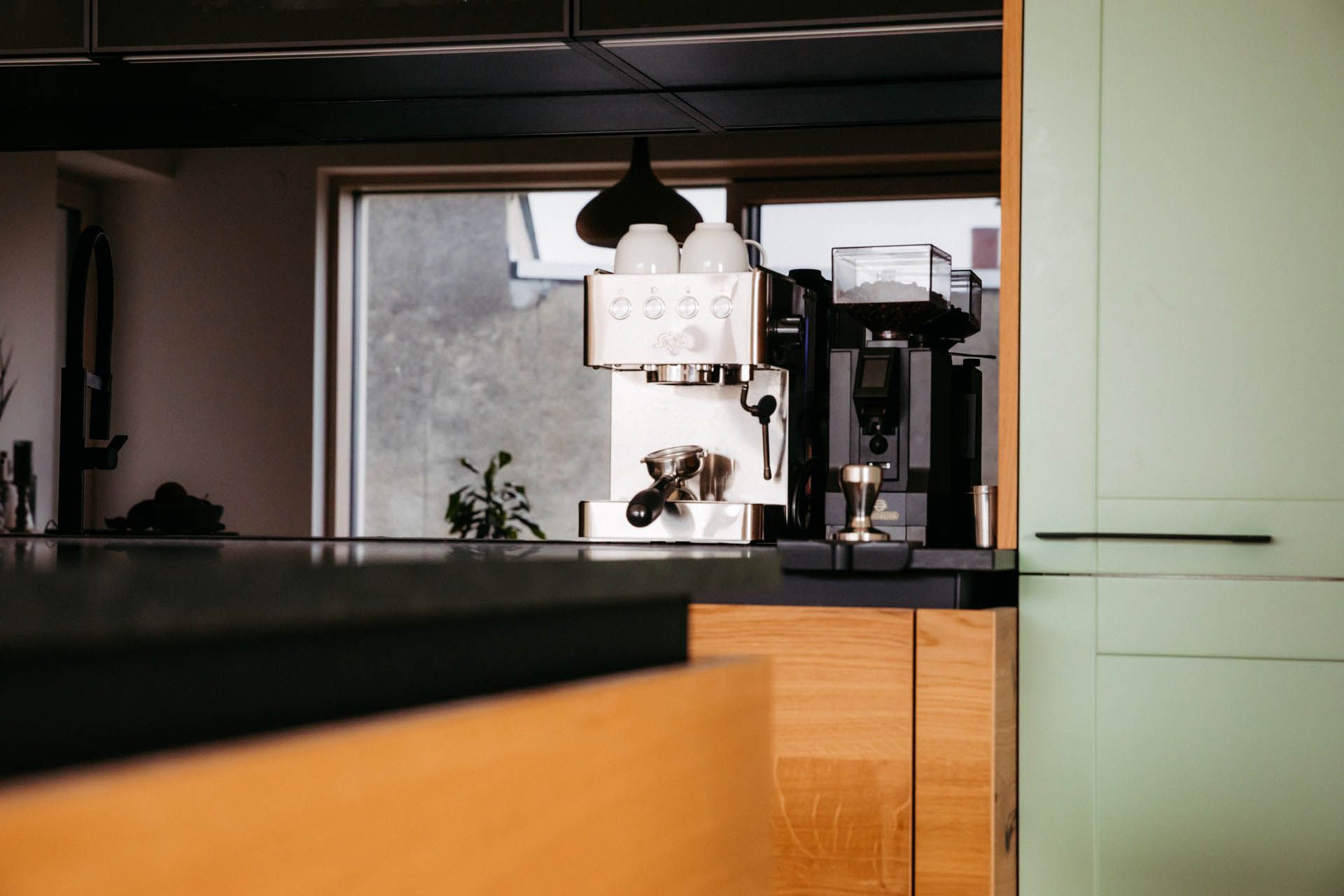 Kaffeemaschine in einer modernen Küche mit grünen Holzschränken.