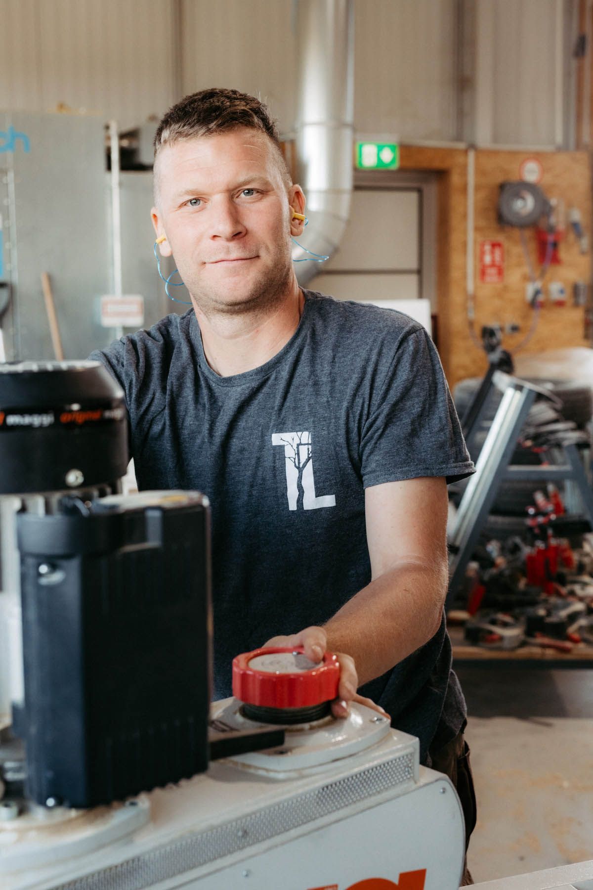 Lächelnder Mann in der Werkstatt, der Maschinen mit einem roten Knopf bedient.