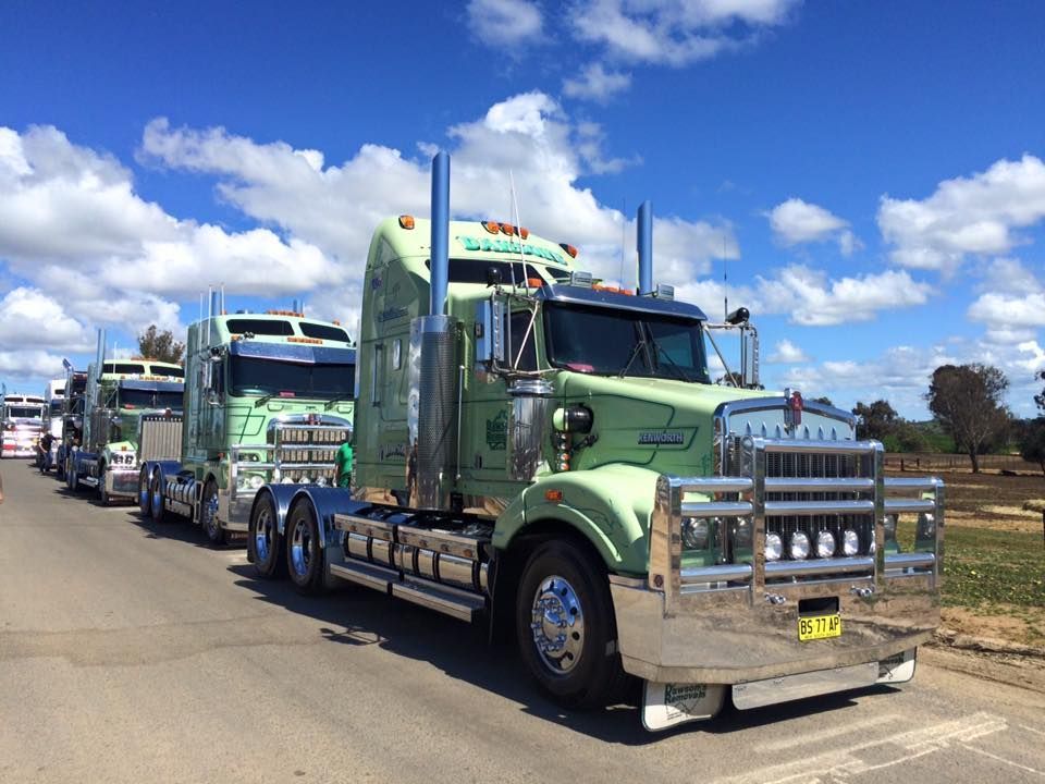 Green Semi Trucks Lined up On a Road Under a Bright Blue Sky with Clouds — Dawson's Removals In Kelso, NSW