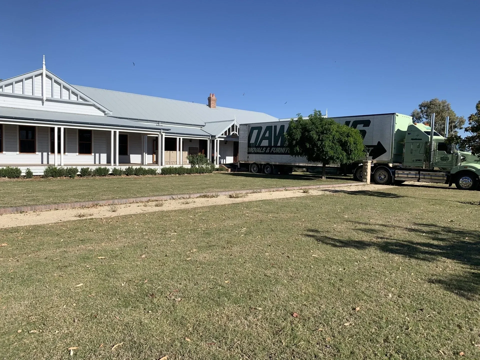 Green Semi-truck Parked in Front of a White Historic Building — Dawson's Removals In Kelso, NSW