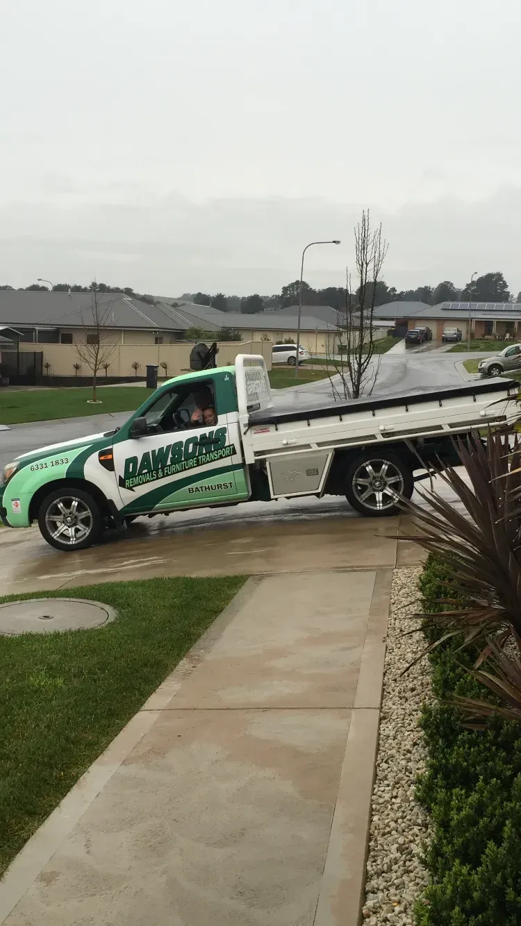 A Green and White Service Truck Parked on a Driveway in a Residential Area — Dawson's Removals In Dubbo, NSW