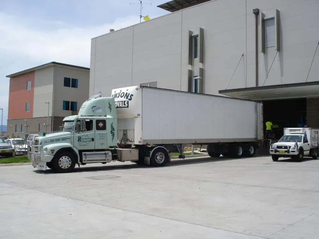 A large semi-truck unloading at a warehouse loading dock on a sunny day — Dawson's Removals In Kelso, NSW