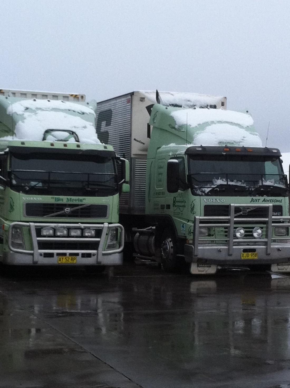 Two Green Refrigerated Trucks Parked Side by Side on A Wet Lot in The Rain — Dawson's Removals In Kelso, NSW
