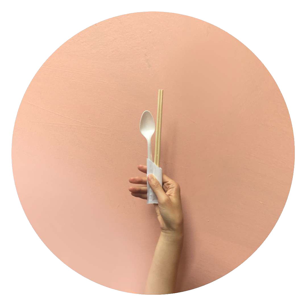 A person is holding a spoon and chopsticks in their hand.