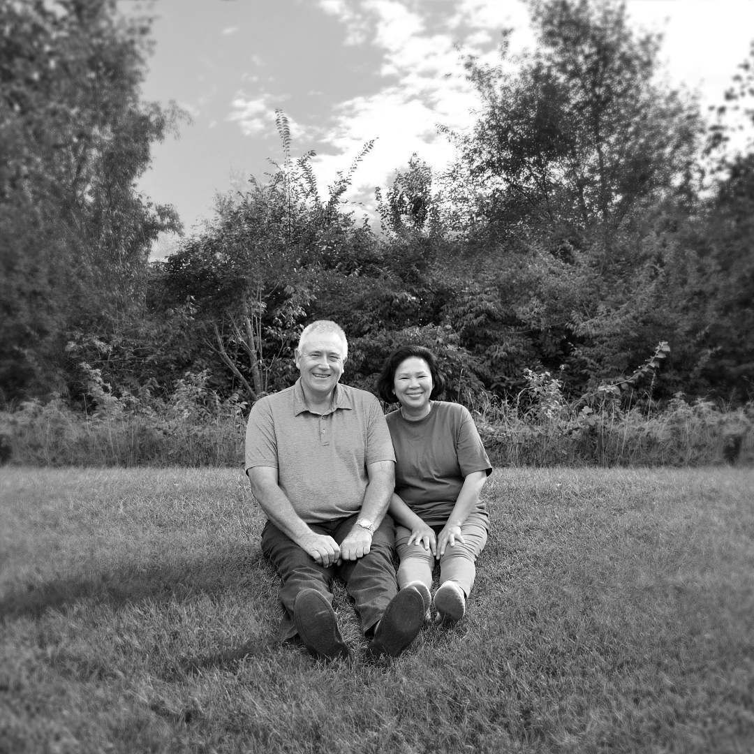 A man and a woman are sitting on the grass in a black and white photo.