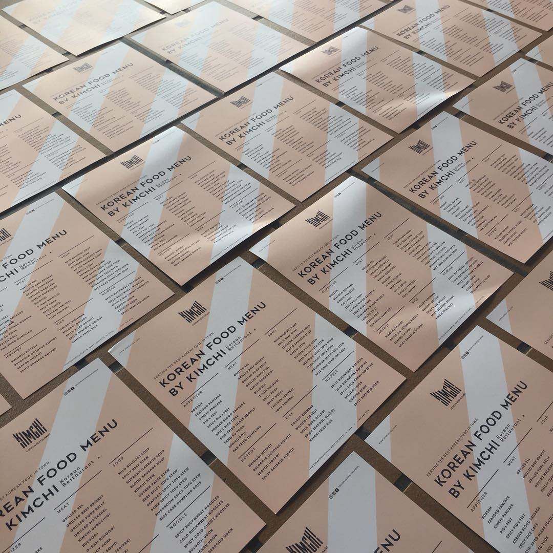 A bunch of korean food menus are laid out on a table