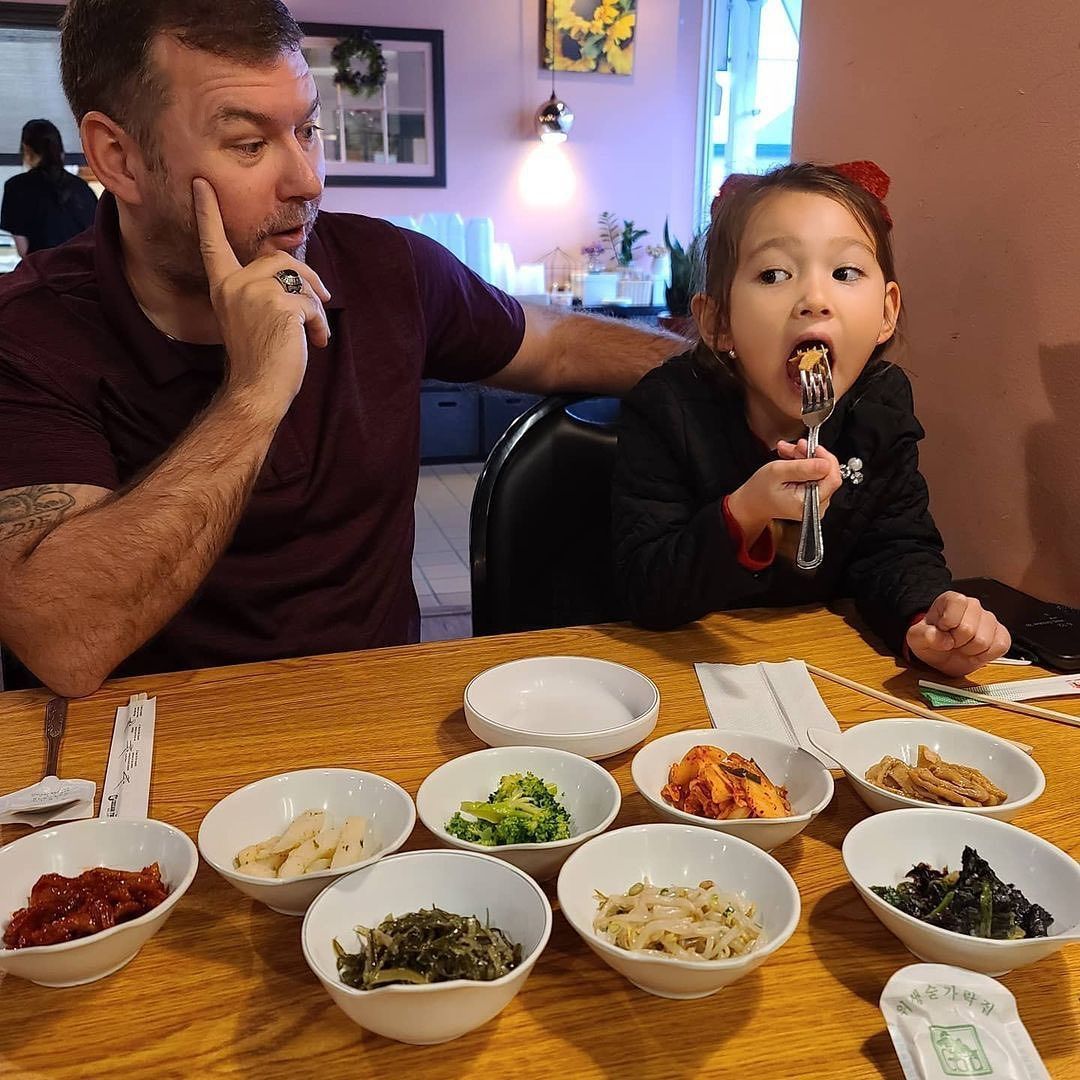 A man and a little girl are sitting at a table with bowls of food.