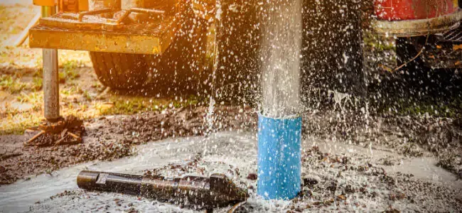 A person is working on a water pump with a wrench.