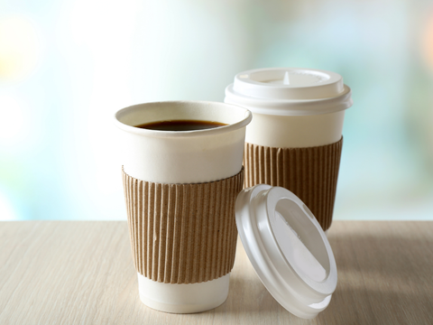 Two cups of coffee are sitting on a wooden table.