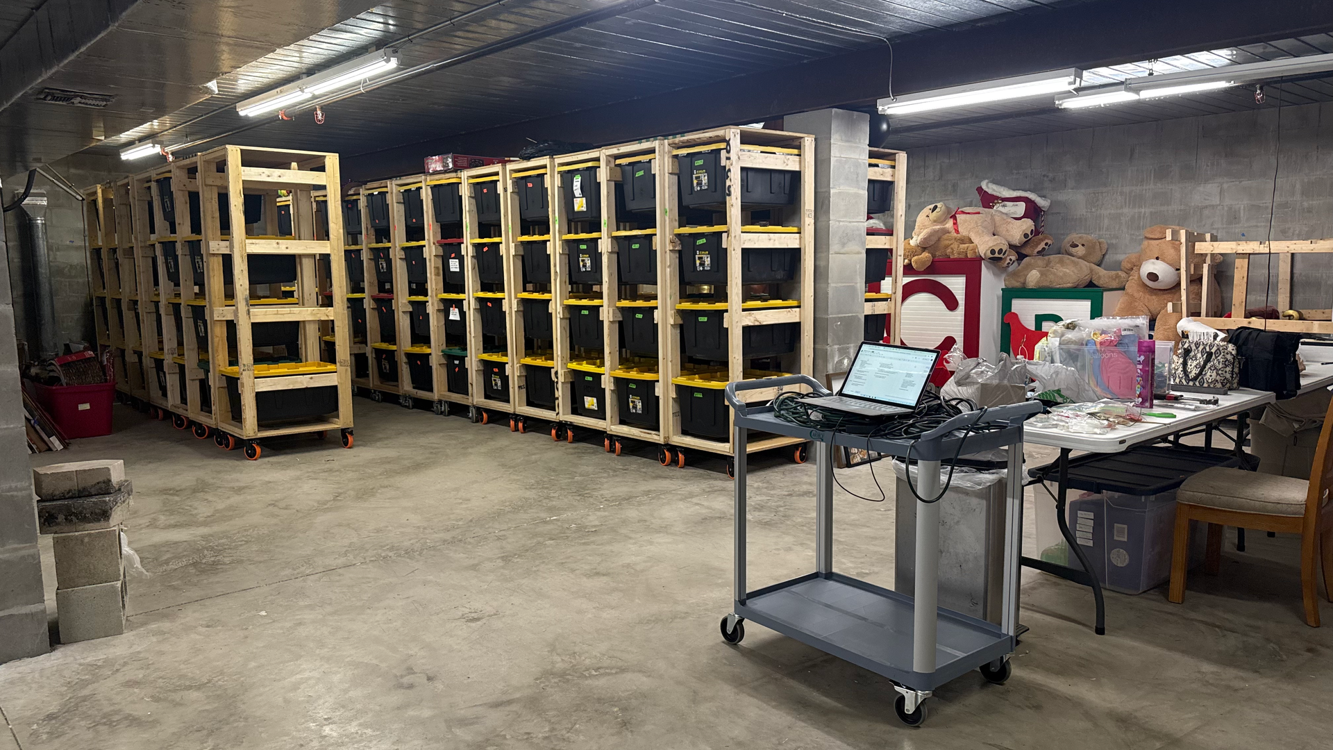 A warehouse with a lot of shelves and a laptop on a cart.