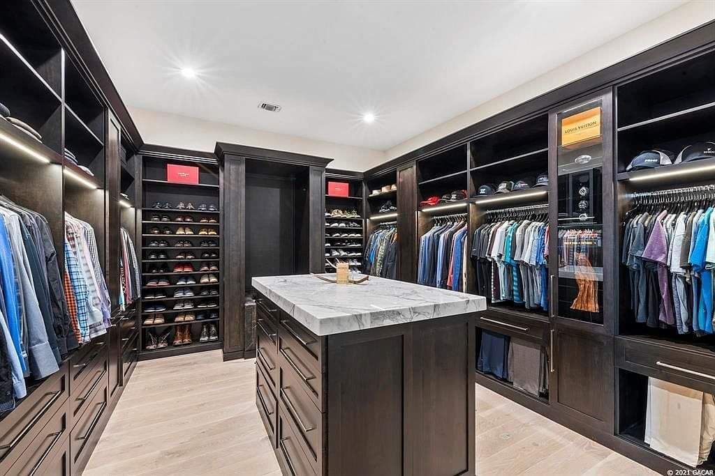 A large walk in closet with a large island in the middle.