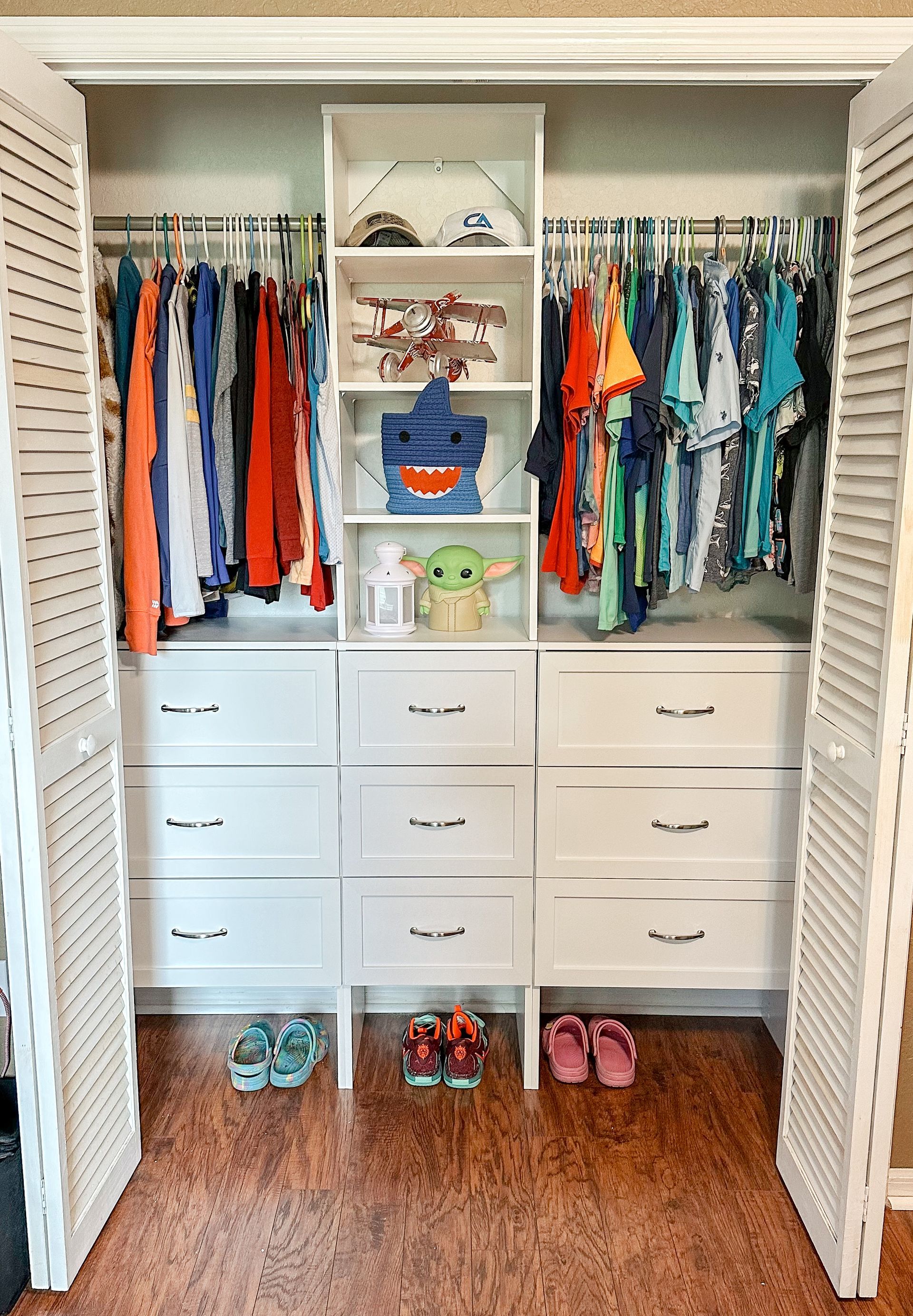 A closet filled with clothes , shoes , and a stuffed animal.