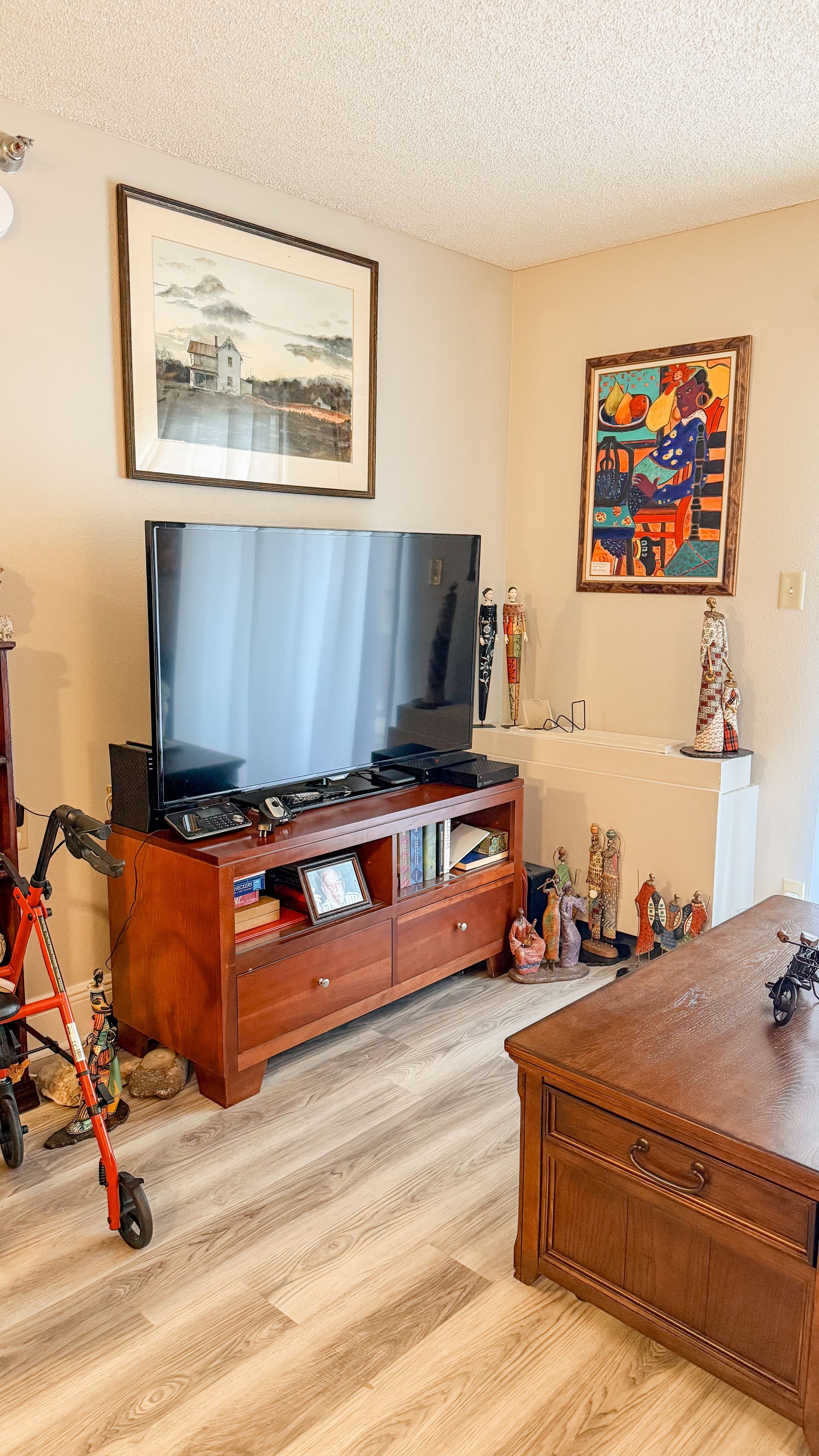 A living room with a flat screen tv on a wooden entertainment center.