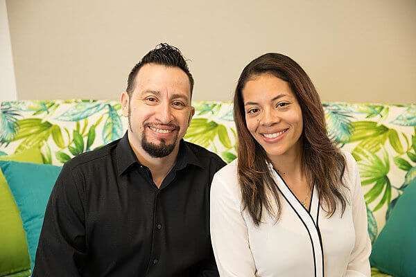 A man and a woman are posing for a picture while sitting on a couch.