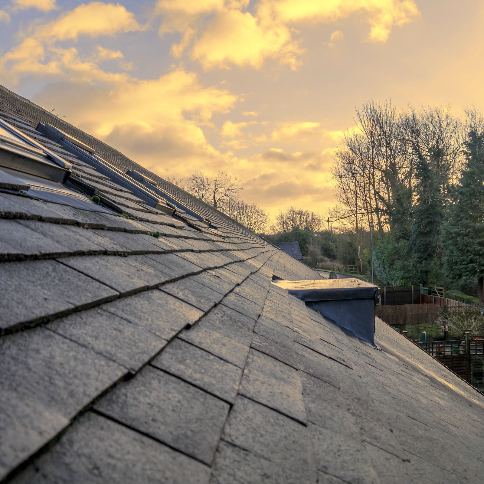 The roof of a house with a sunset in the background