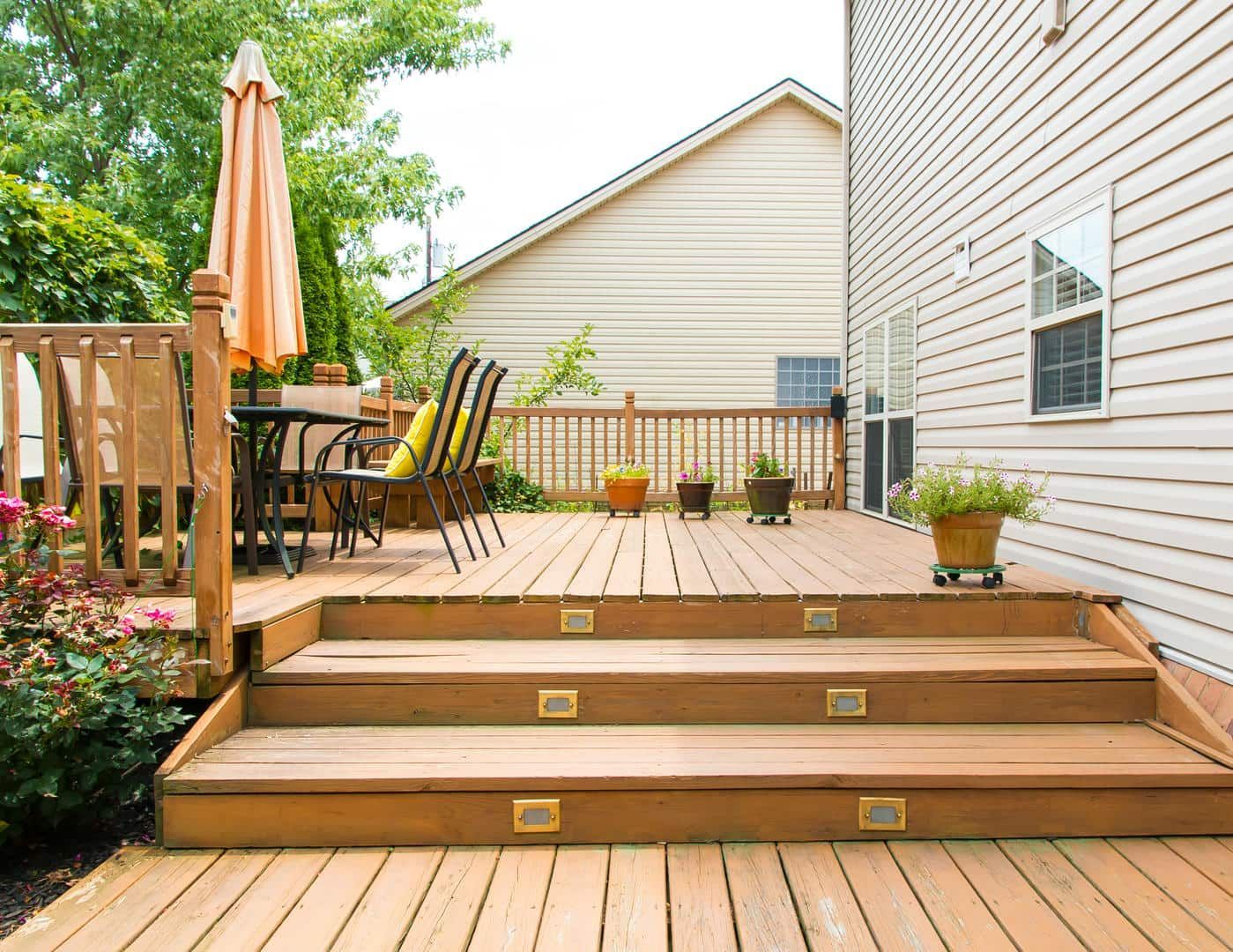 A wooden deck with stairs leading up to it and a table and chairs on it.