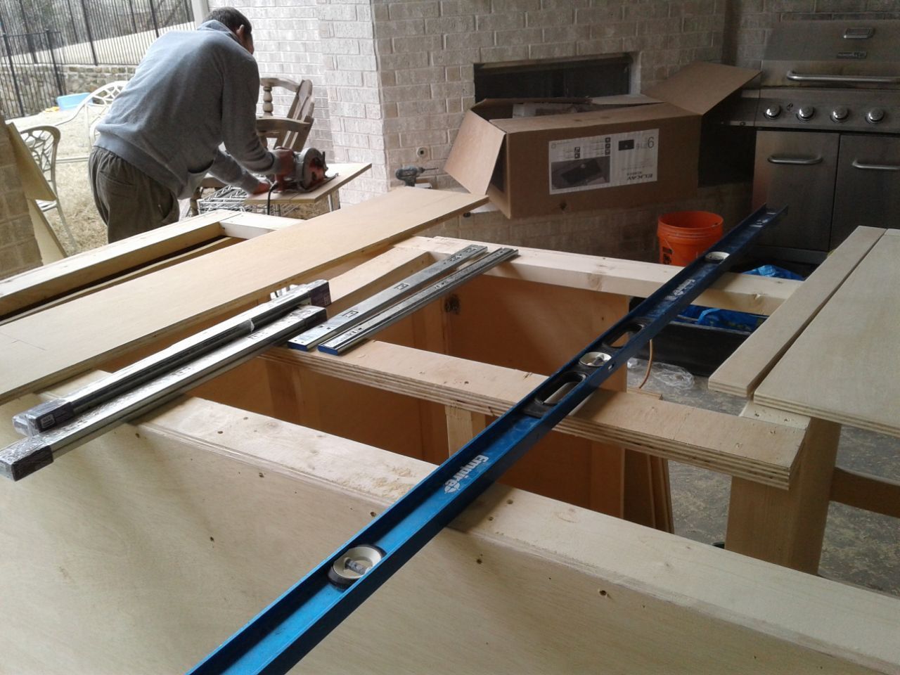 Person using a saw on a construction project, measuring with a level on a wood surface.