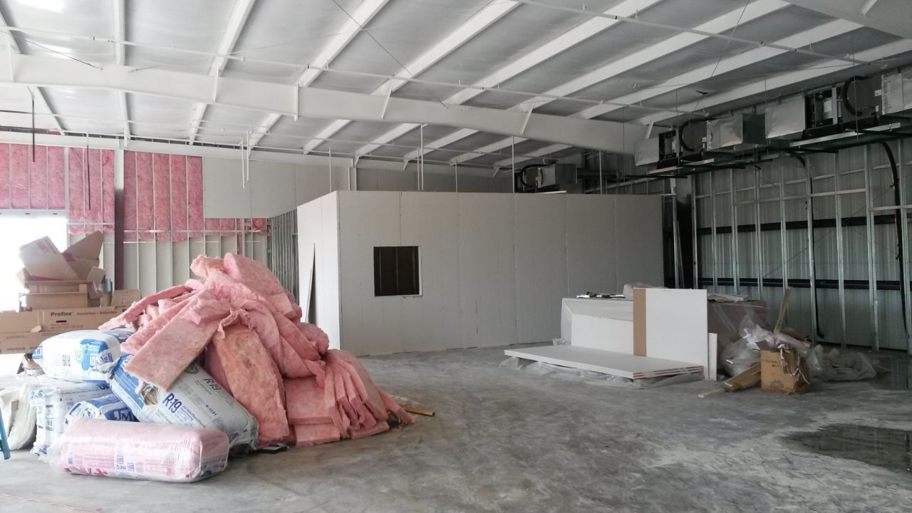 Interior of a building under construction, showing insulation, drywall, and exposed metal framing.