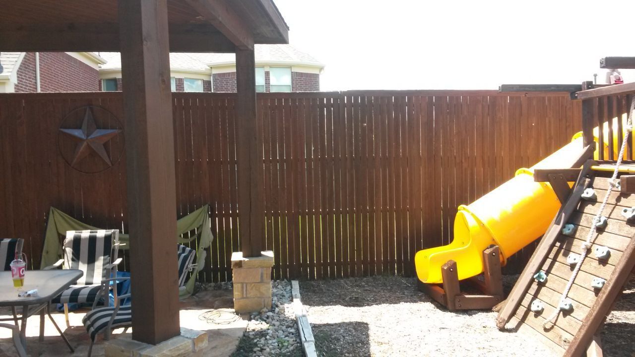 Playground area with wooden fence, slide, gazebo, and patio furniture.