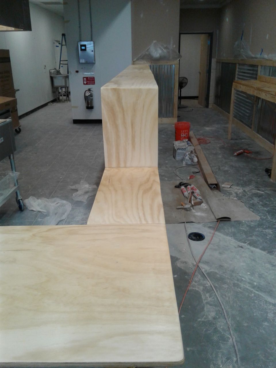 Unfinished wooden counter in a room under construction, with tools and materials nearby.