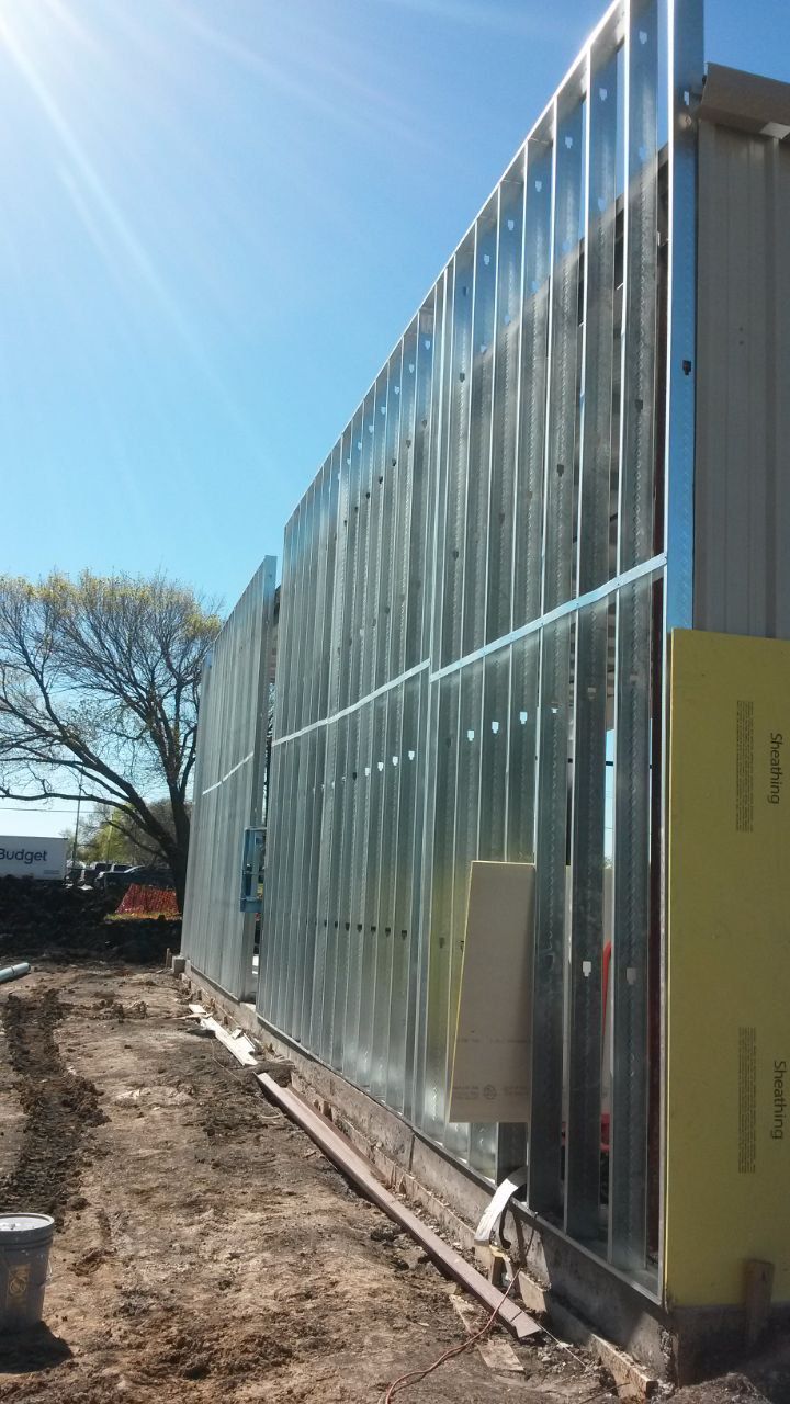 Metal framing of a building under construction, exterior view with blue sky, sunny day.