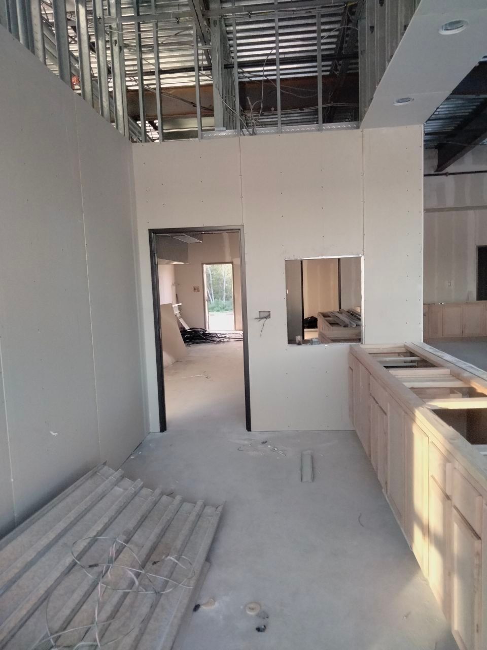 Interior under construction; drywall and framing visible. Unfinished kitchen with a doorway.
