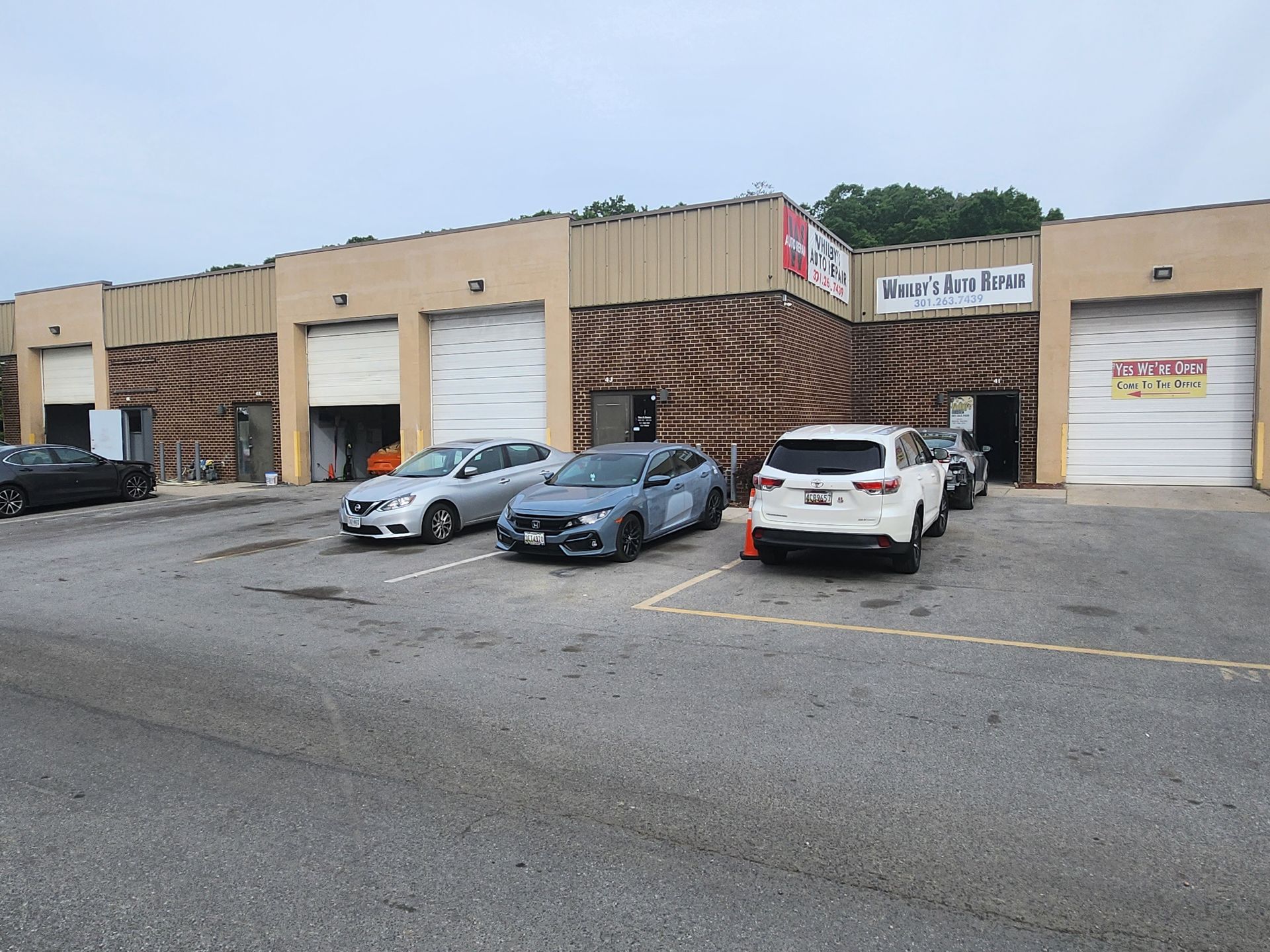 A row of cars are parked in front of a building.