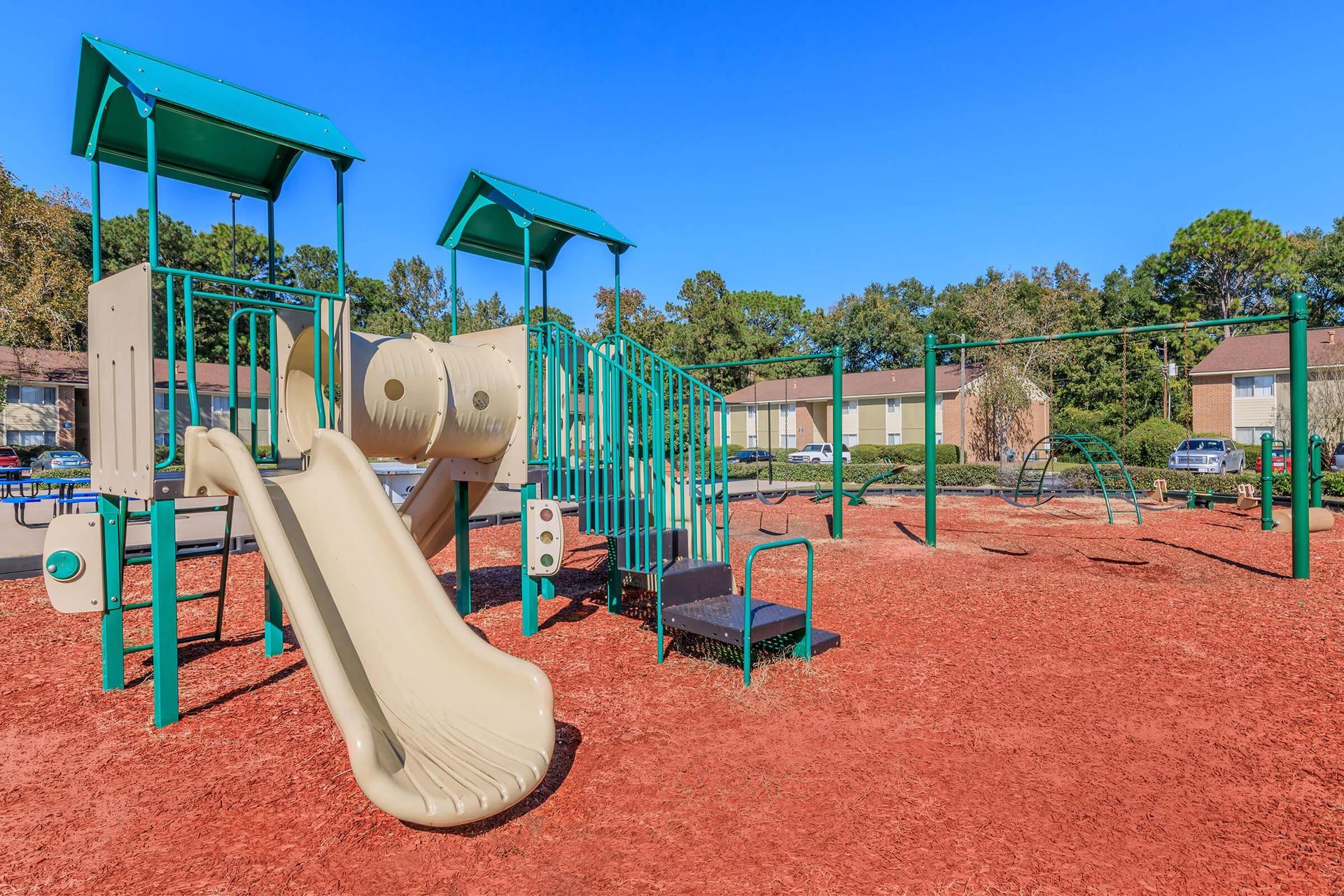 A playground with a slide , swings , and a bench.