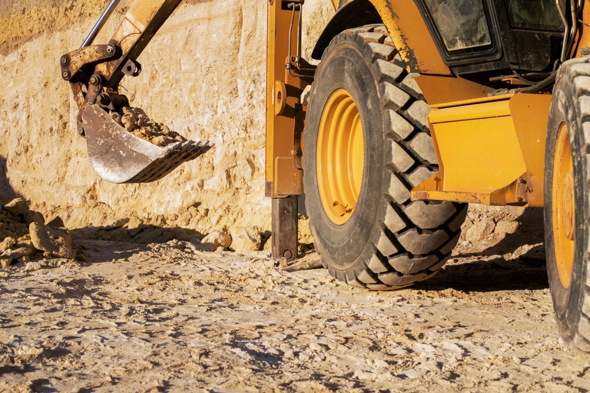 A yellow excavator is digging a hole in the dirt.