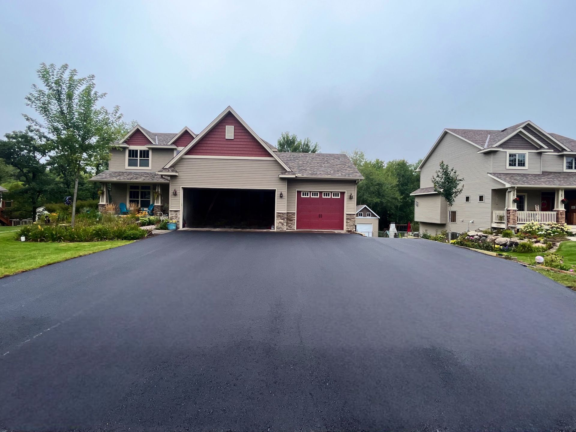 A driveway leading to a house with a red garage door.