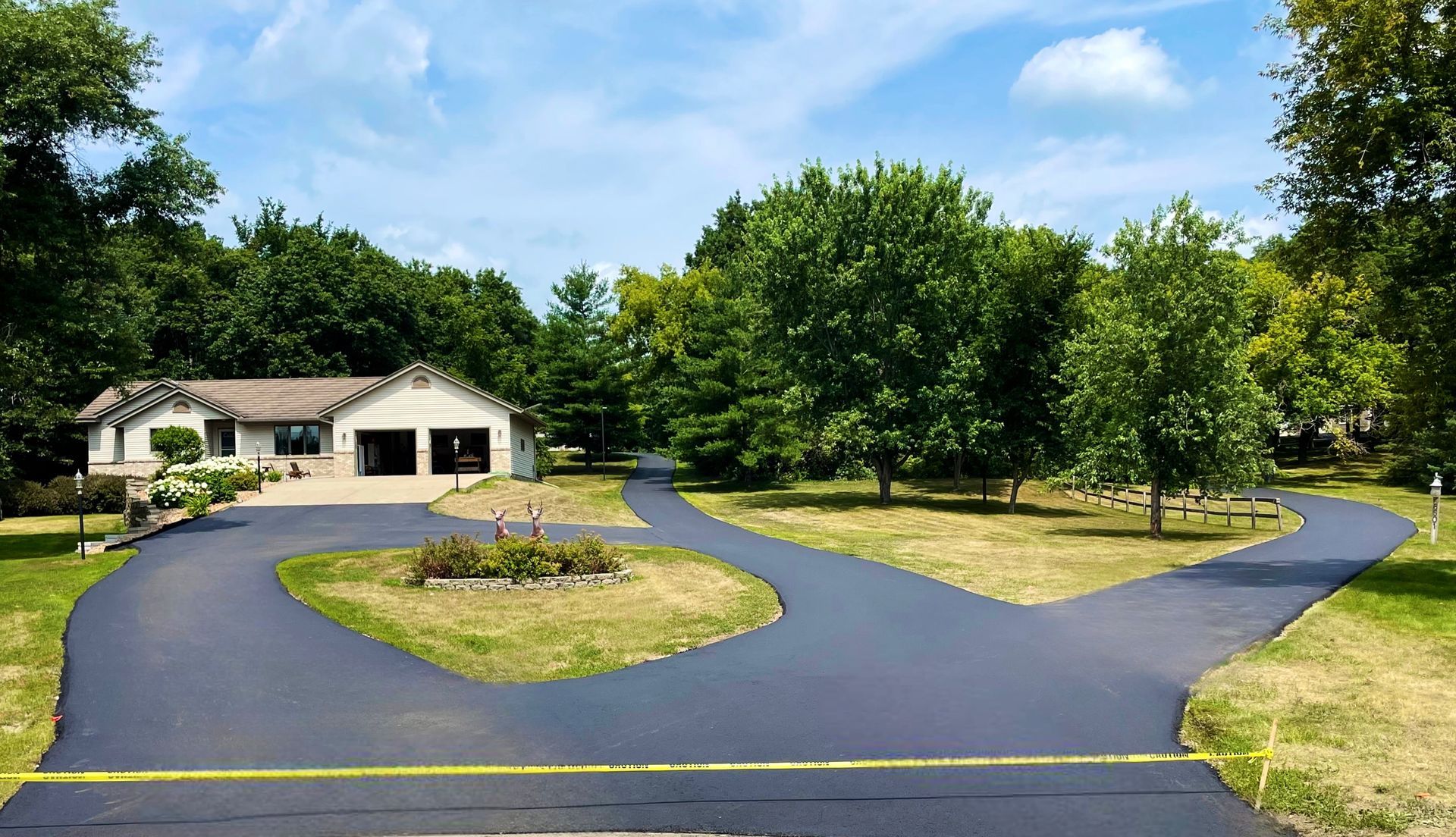 A driveway leading to a house surrounded by trees and grass.