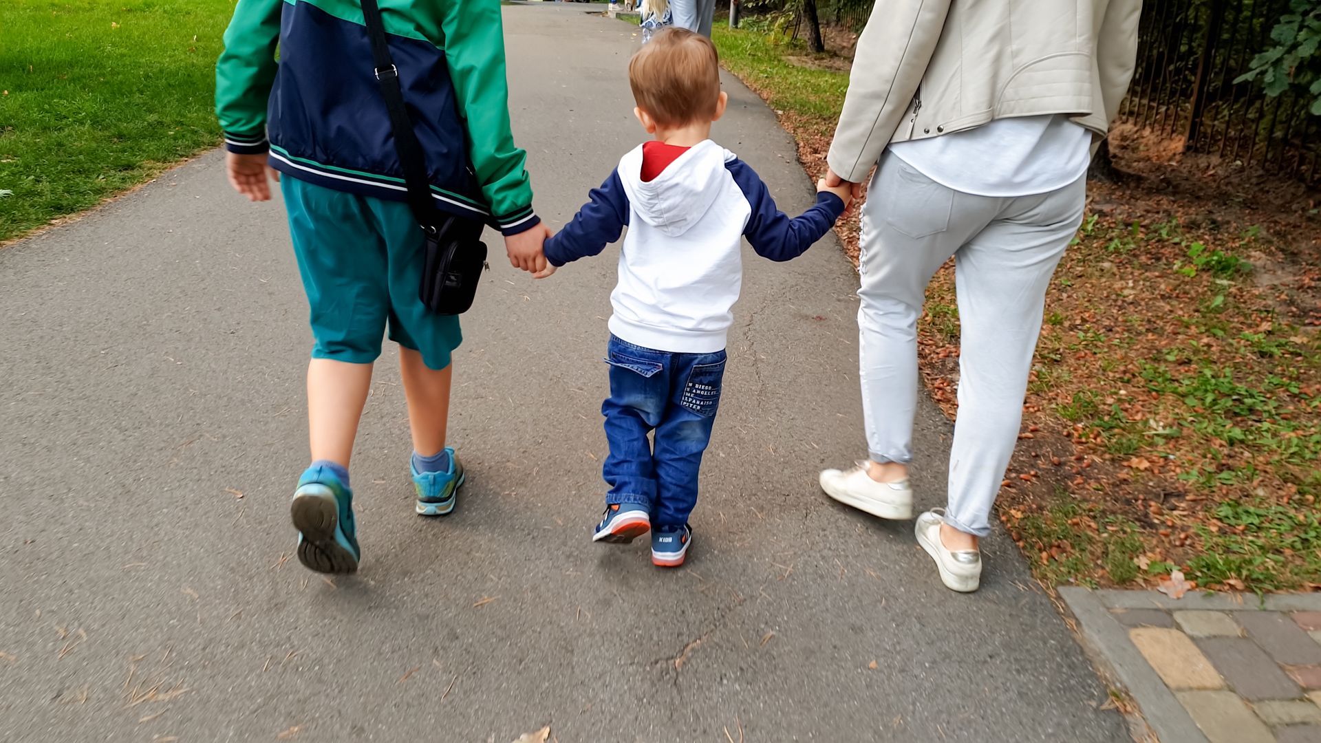 A woman and two children are walking down a path holding hands.