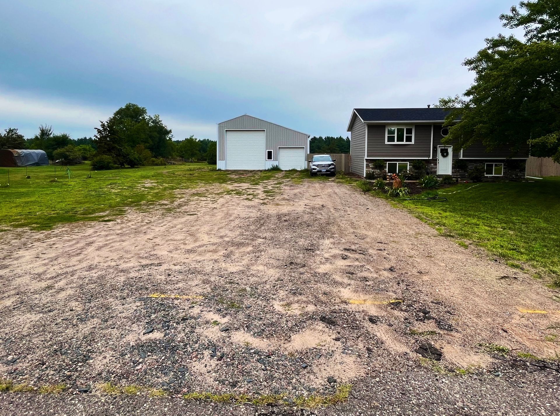 a gravel driveway with a garage and a car in the back